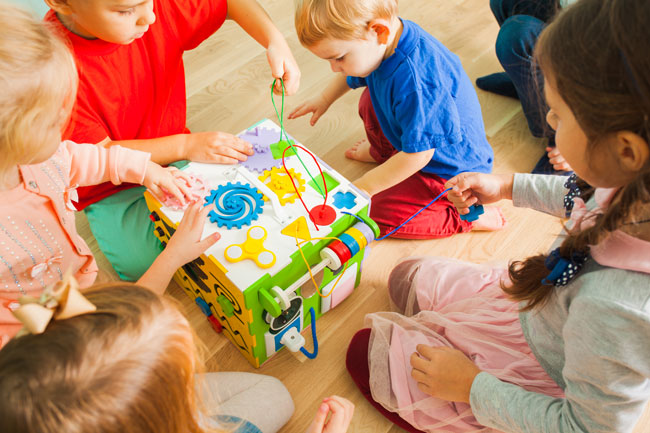 Niños jugando juntos con un cubo de actividades
