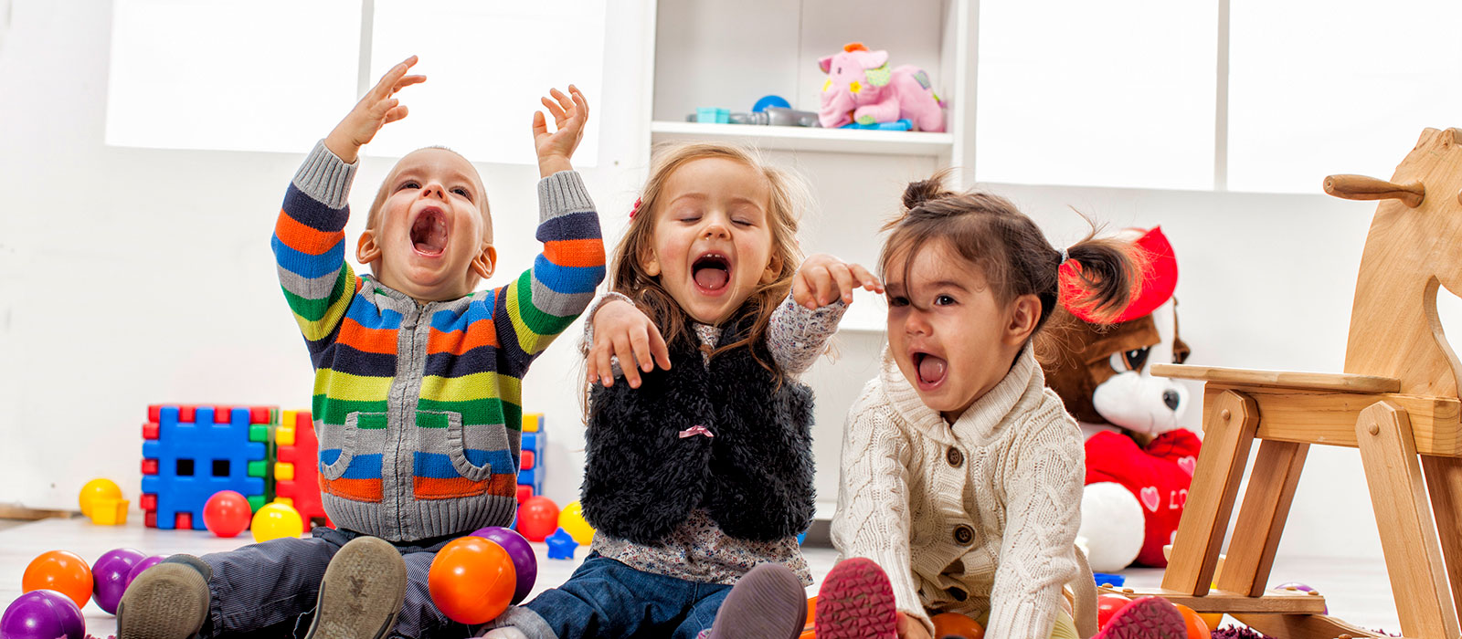 Tres niños riendo y jugando con pelotas